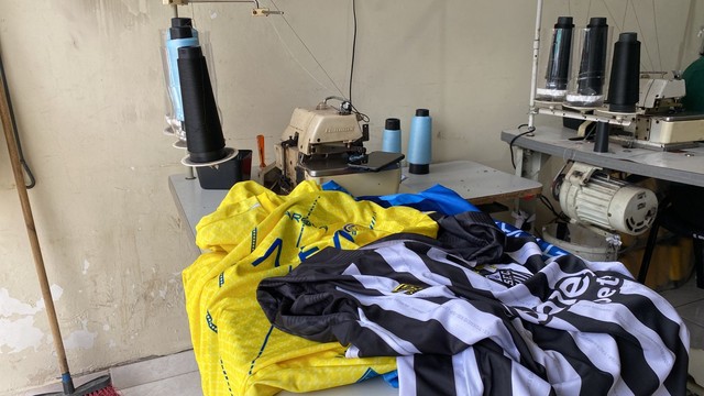 Camisas falsas em cima da mesa com máquina de costura. (Foto: Reprodução/TV Vanguarda/Rauston Naves) Lorena Bueri