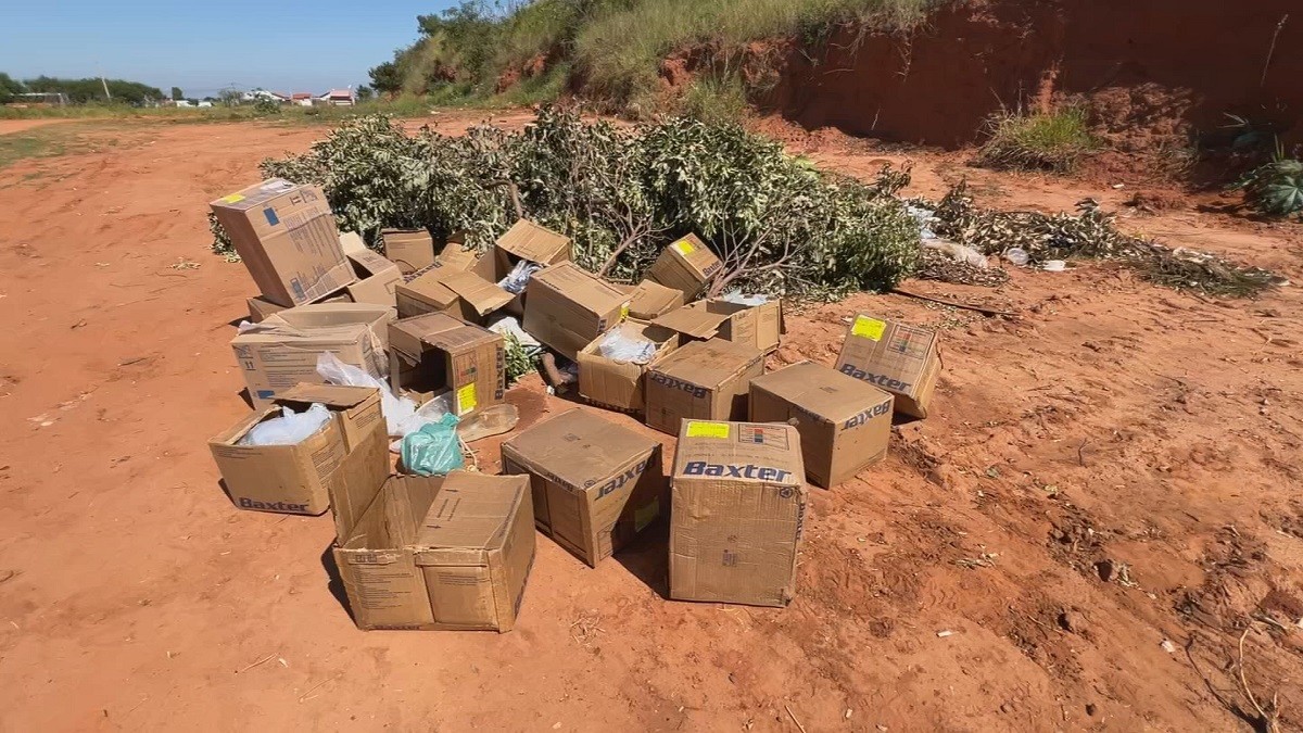 Caixas com seringas e insumos médicos são descartadas em rua de terra em Bauru