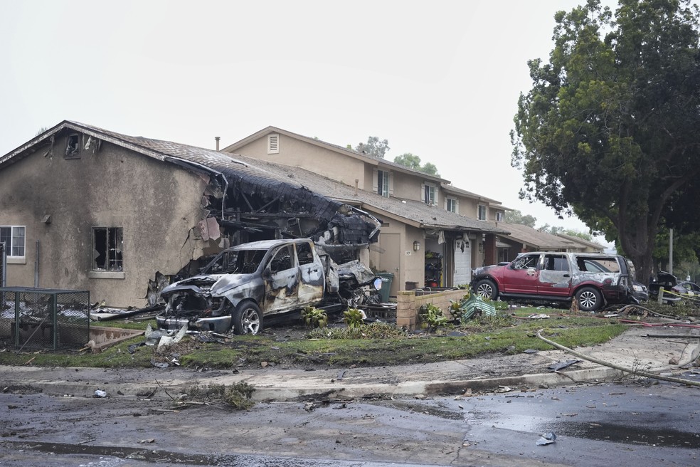 Veículos e casas danificados por queda de avião de pequeno porte em bairro de San Diego em 22 de maio de 2025. — Foto: AP Photo/Gregory Bull