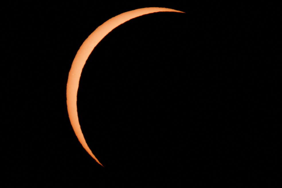 A Lua encobre parcialmente o Sol durante o eclipse solar visto de Arija, na Espanha, nesta quarta-feira (12). — Foto: Borja Suarez/Reuters