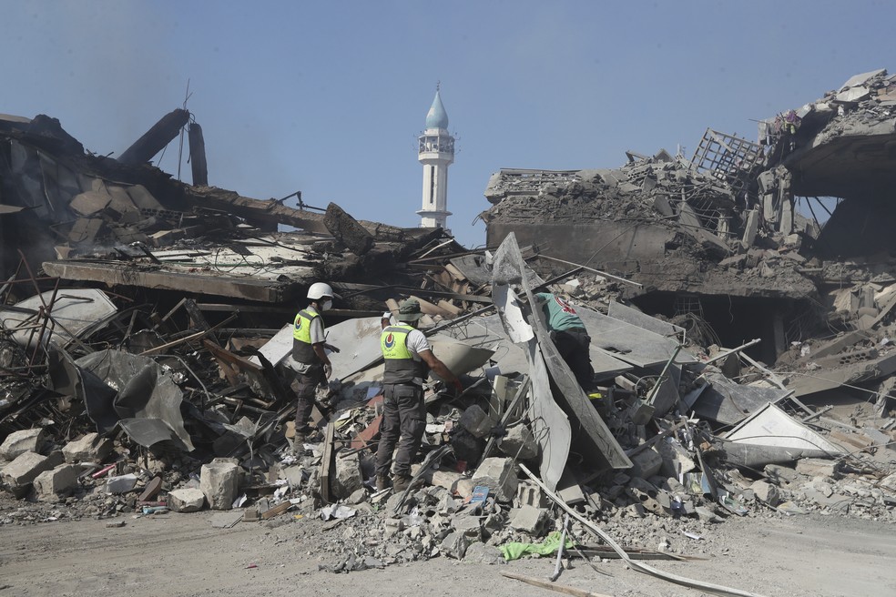 Resgatistas do Hezbollah buscam vítimas entre prédios destruídos em uma rua comercial atingida por ataques aéreos israelenses do último sábado (12), na cidade de Nabatiyeh, no sul do Líbano. — Foto: AP Foto/Mohammed Zaatari