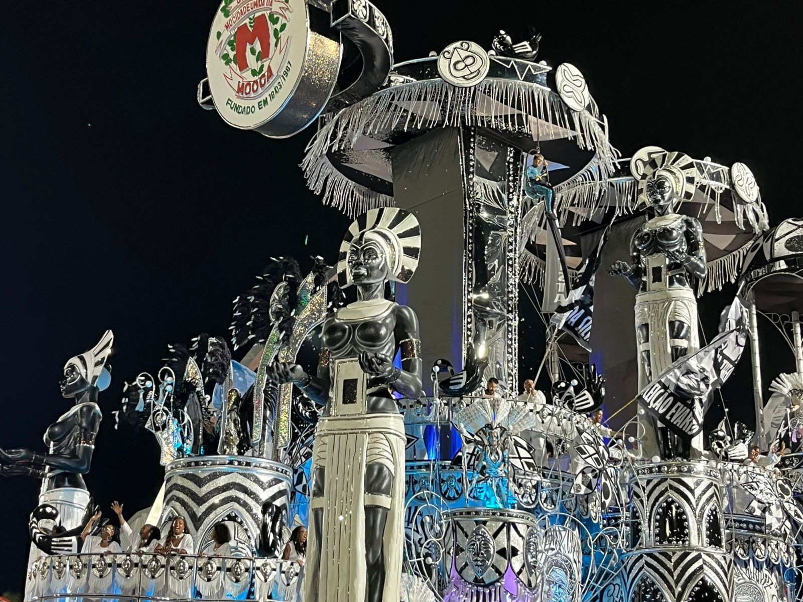 Acrobata de 15 anos se pendura em carro alegórico e ajuda a levar faixa antirracista no desfile da MUM