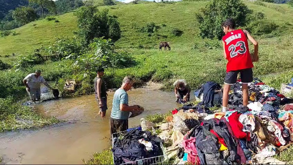 Comerciante de Mimoso do Sul tenta recuperar mercadoria atingida por lama de enxurrada e lava 11 mil peças de roupas em córrego.  — Foto: Arquivo pessoal