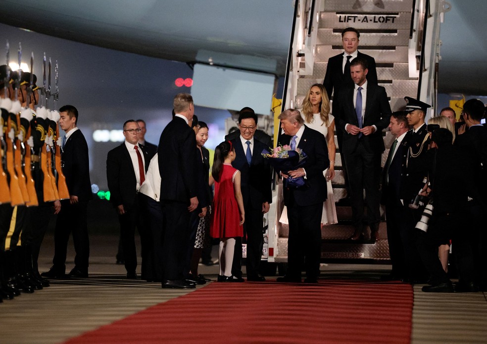 O bilionário Elon Musk (ao fundo) desce escadas após desembarcar do Air Force One atrás do presidente dos EUA, Donald Trump, em Pequim, na China, em 13 de maio de 2026. — Foto: Evan Vucci/ Reuters