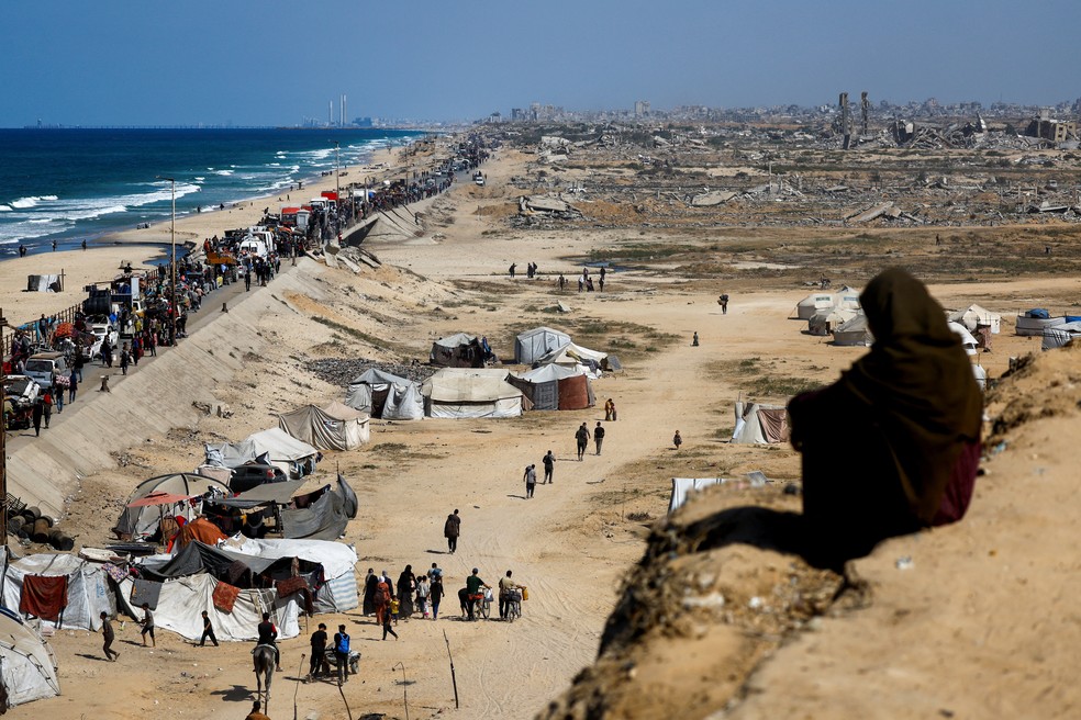 Palestinos, que foram deslocados para a parte sul de Gaza por ordem de Israel durante a guerra, seguem por uma estrada enquanto retornam ao norte, durante um cessar-fogo entre Israel e o Hamas em Gaza, na região central da Faixa de Gaza, em 11 de outubro — Foto: Mahmoud Issa/Reuters