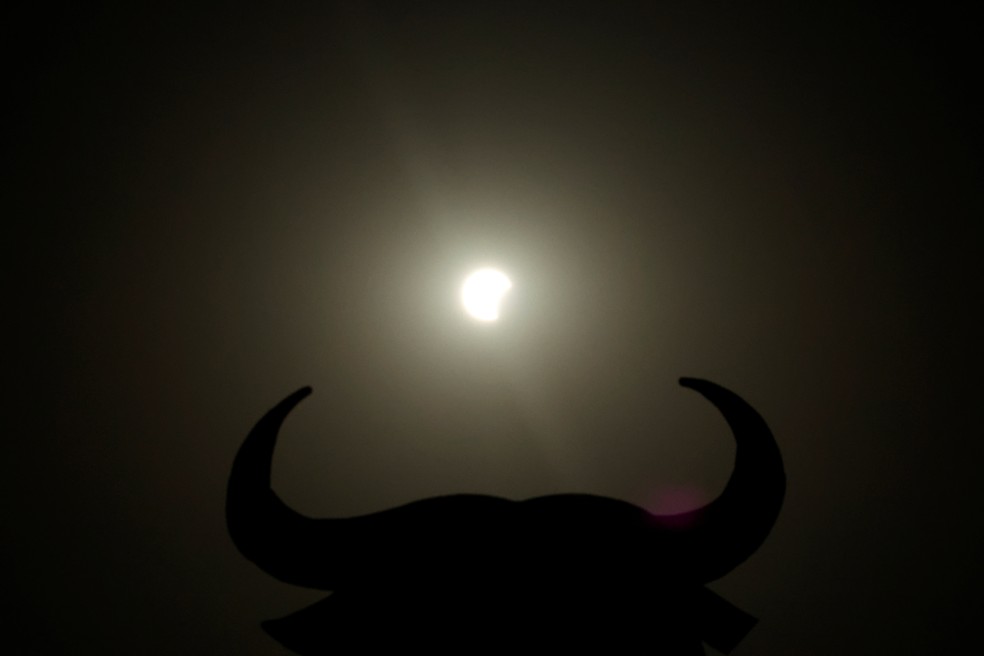 O Sol aparece próximo à silhueta de um Touro de Osborne antes da fase de totalidade do eclipse, em Navarrete, no norte da Espanha, nesta quarta-feira (12). — Foto: Vincent West/Reuters