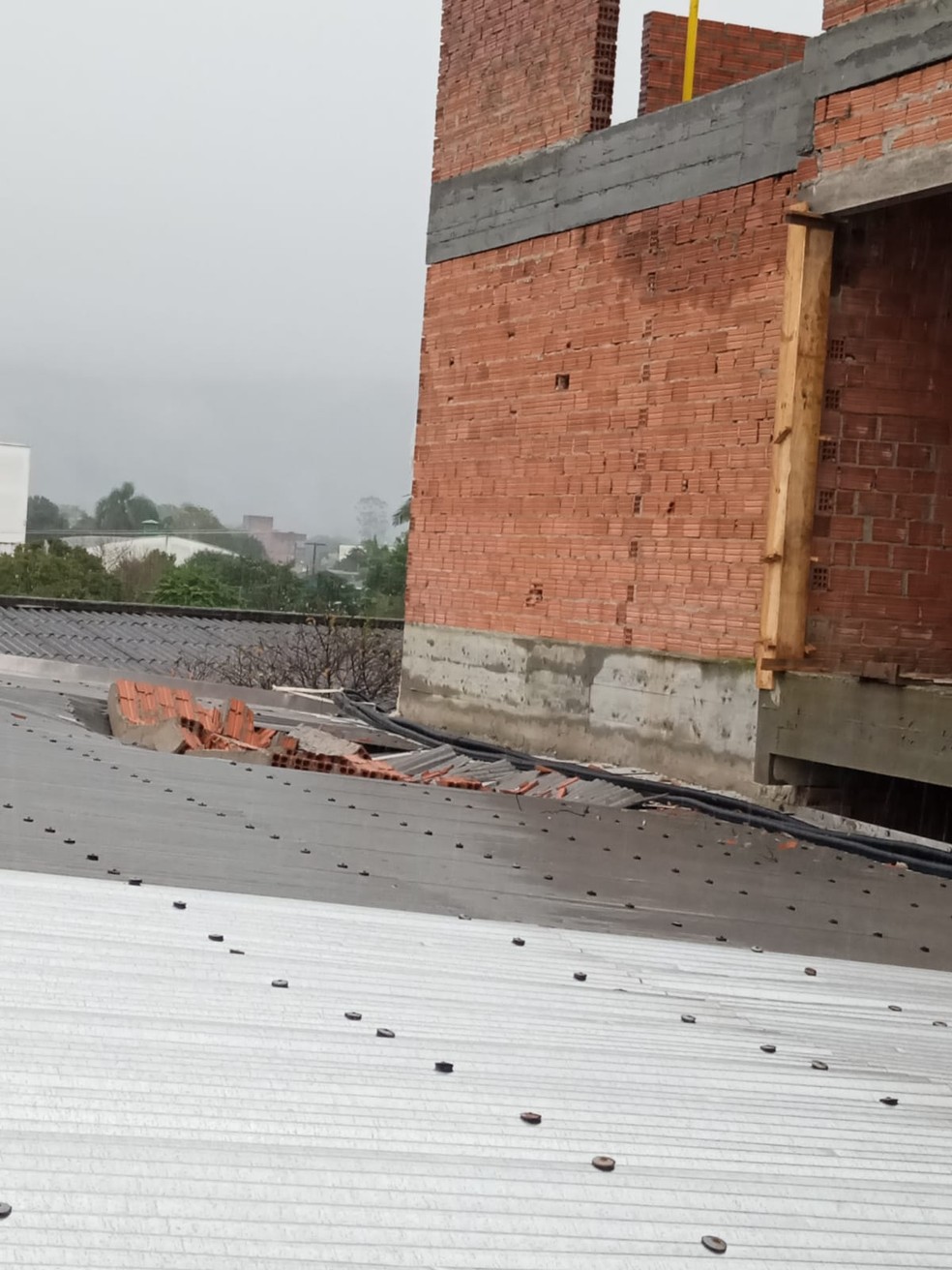 Força do vento e chuva derrubam estrutura em construção em cima de telhado de hospital em Praia Grande — Foto: NSC TV/Reprodução