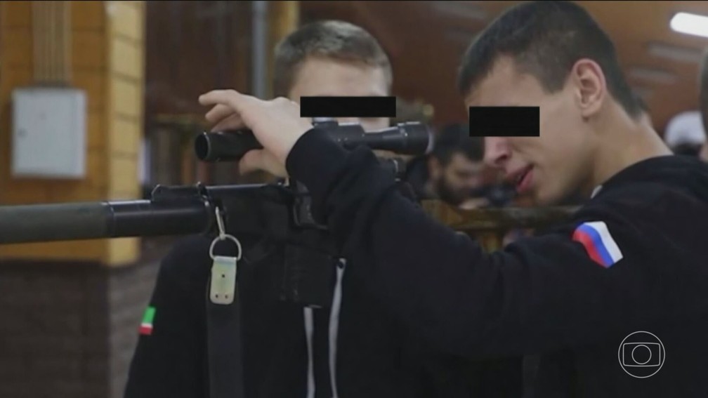Adolescente em aula de tiro com uniforme com bandeira da Rússia — Foto: JN