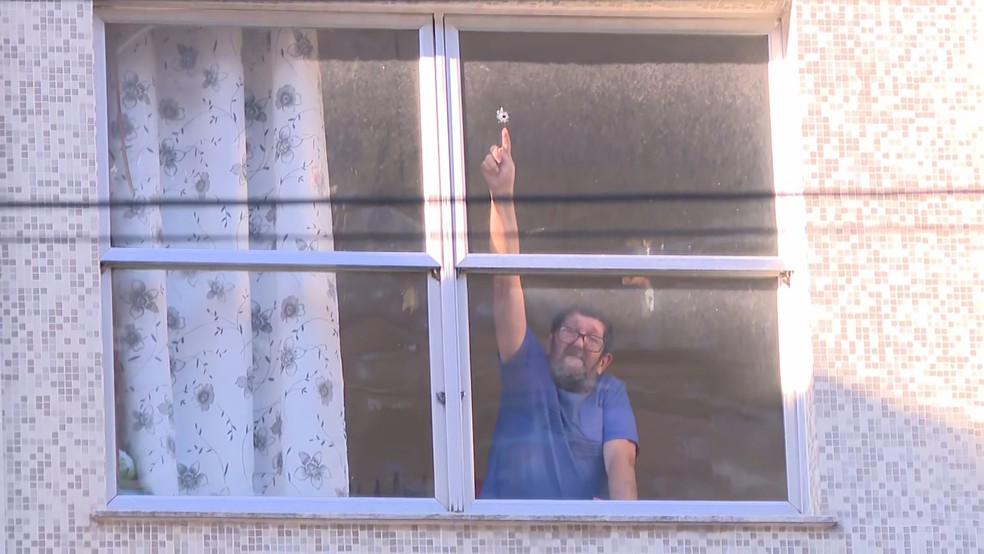 Morador da São Clemente aponta para buraco de bala na janela — Foto: Reprodução/TV Globo