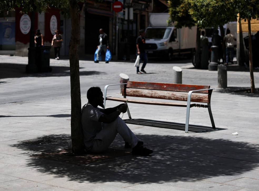 Um homem senta-se à sombra de uma árvore para escapar do calor durante uma onda de calor em Madrid, Espanha — Foto: REUTERS/Mohammed Salem