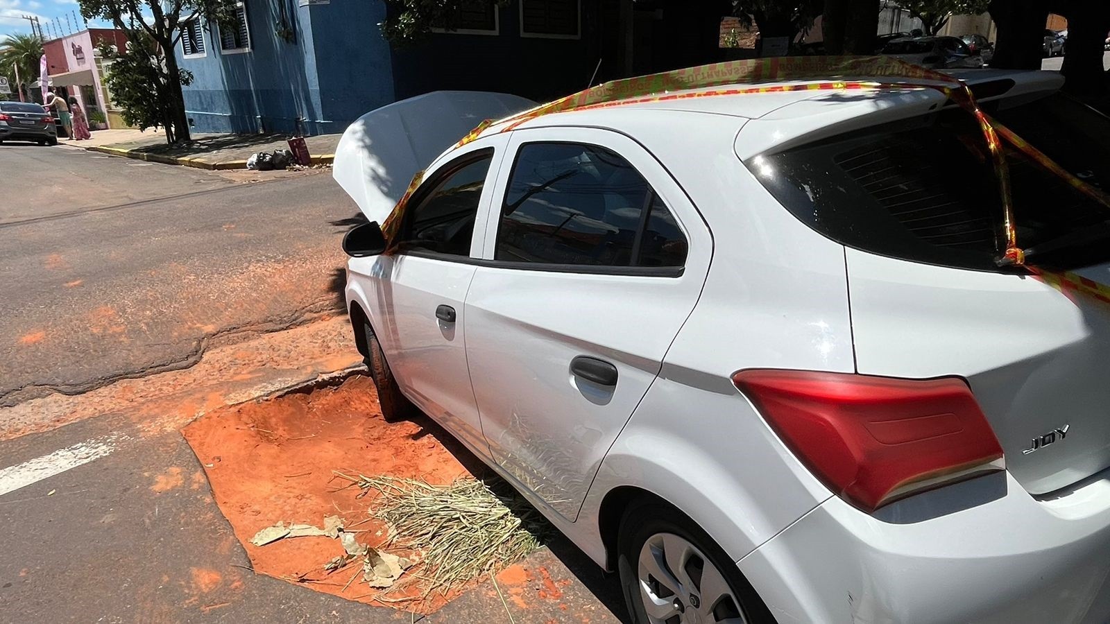 Carro fica preso em buraco no asfalto no cruzamento entre as ruas Casemiro Dias e 12 de Outubro, em Presidente Prudente