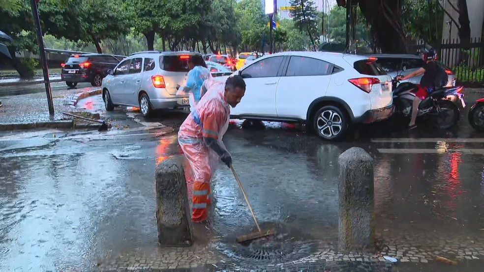 Gari tenta limpar bueiro na Rua Marquês de Olinda, em Botafogo, na Zona Sul do Rio — Foto: Reprodução/ TV Globo