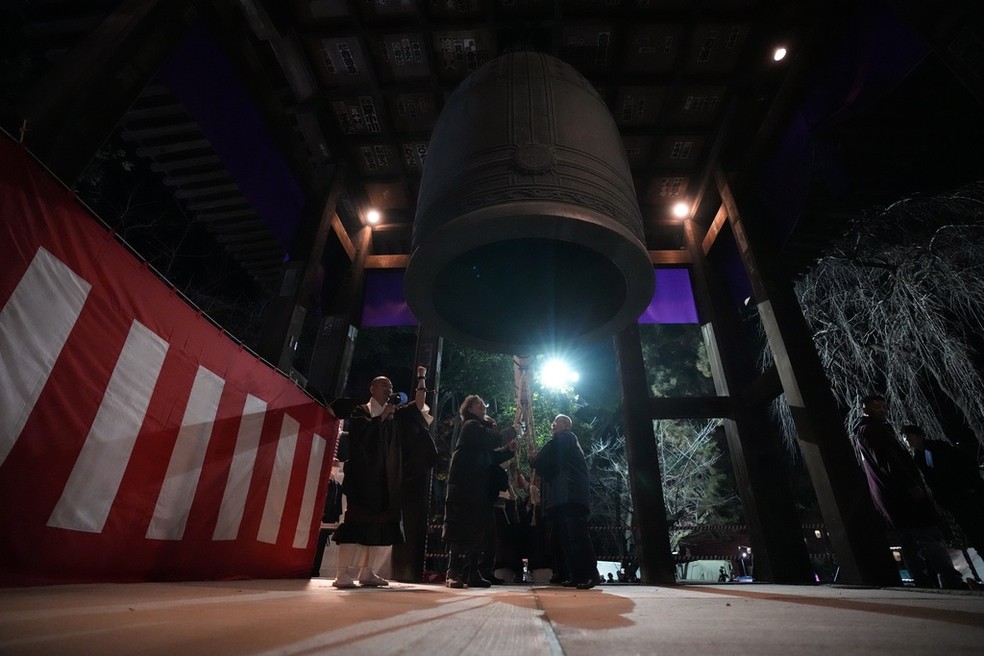 Japoneses tocam um sino gigante para celebrar a entrada de 2024, no templo budista Zojoji, minutos depois da meia-noite de segunda-feira, 1º de janeiro de 2024, em Tóquio — Foto: AP Photo/Eugene Hoshiko