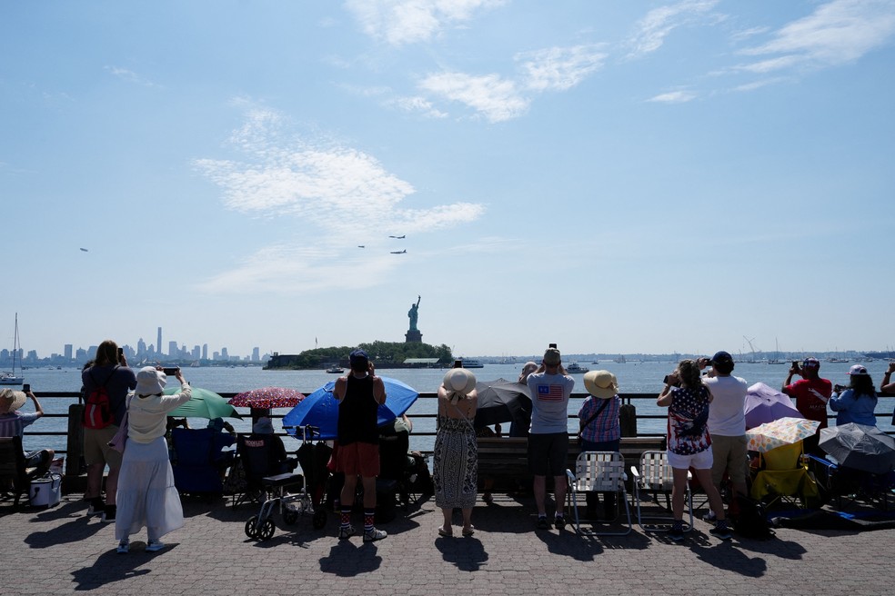 Pessoas acompanham o sobrevoo de aeronaves militares próximo à Estátua da Liberdade durante o desfile de navios Sail 250, no porto de Nova York, enquanto os Estados Unidos celebram o 250º aniversário do país no Dia da Independência. — Foto: Reuters