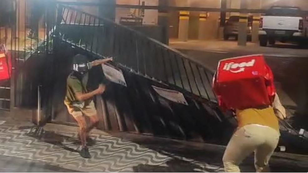 Em represália pela agressão do colega, um grupo de entregadores fez um buzinaço e derrubou o portão do prédio onde o caso ocorreu. — Foto: Reprodução