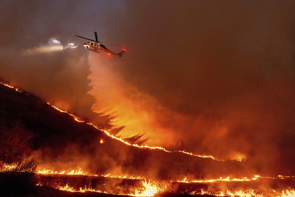 Helicóptero joga água sob as chamas do incêndio Kenneth, em Los Angeles — Foto: Ethan Swope/AP Photo