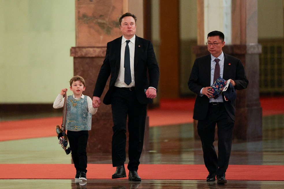 CEO da Tesla, Elon Musk, e seu filho X Æ A-12 caminham no dia em que o Premier chinês Li Qiang se encontra com CEOs americanos, em Pequim. — Foto: REUTERS/Go Nakamura/Pool