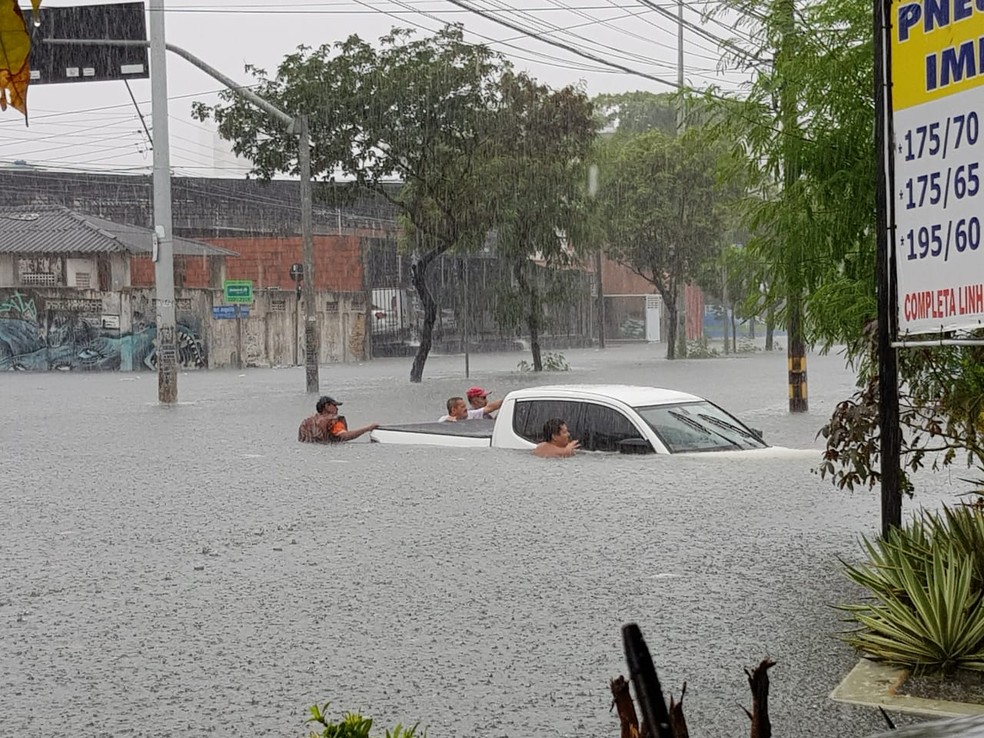 Grupo de homens tentou, sem sucesso, retirar veículo submerso da via — Foto: José Leomar 