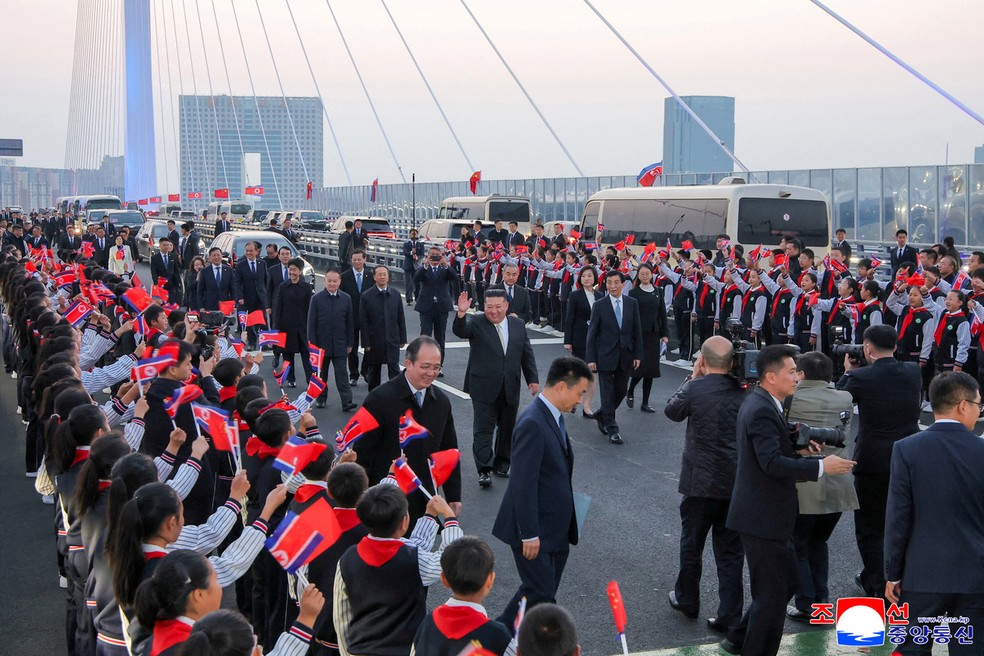 O líder norte-coreano, Kim Jong-un, caminha ao lado de Wang Huning, presidente do Comitê Nacional da Conferência Consultiva Política do Povo Chinês (CPPCC, na sigla em inglês), pela Nova Ponte do Rio Yalu, que liga Dandong, na China, a Sinuiju, na Coreia do Norte, durante visita à cidade chinesa, na província de Liaoning, em 24 de outubro de 2026. — Foto: KCNA via REUTERS