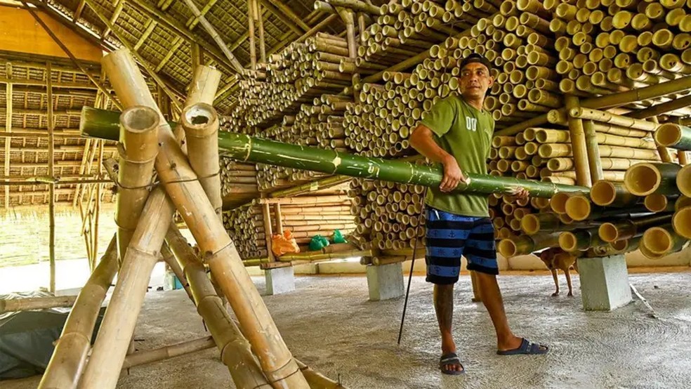 Trabalhador posiciona um caule de bambu verde em um centro de tratamento do material nas Filipinas — Foto: Base Bahay Foundation