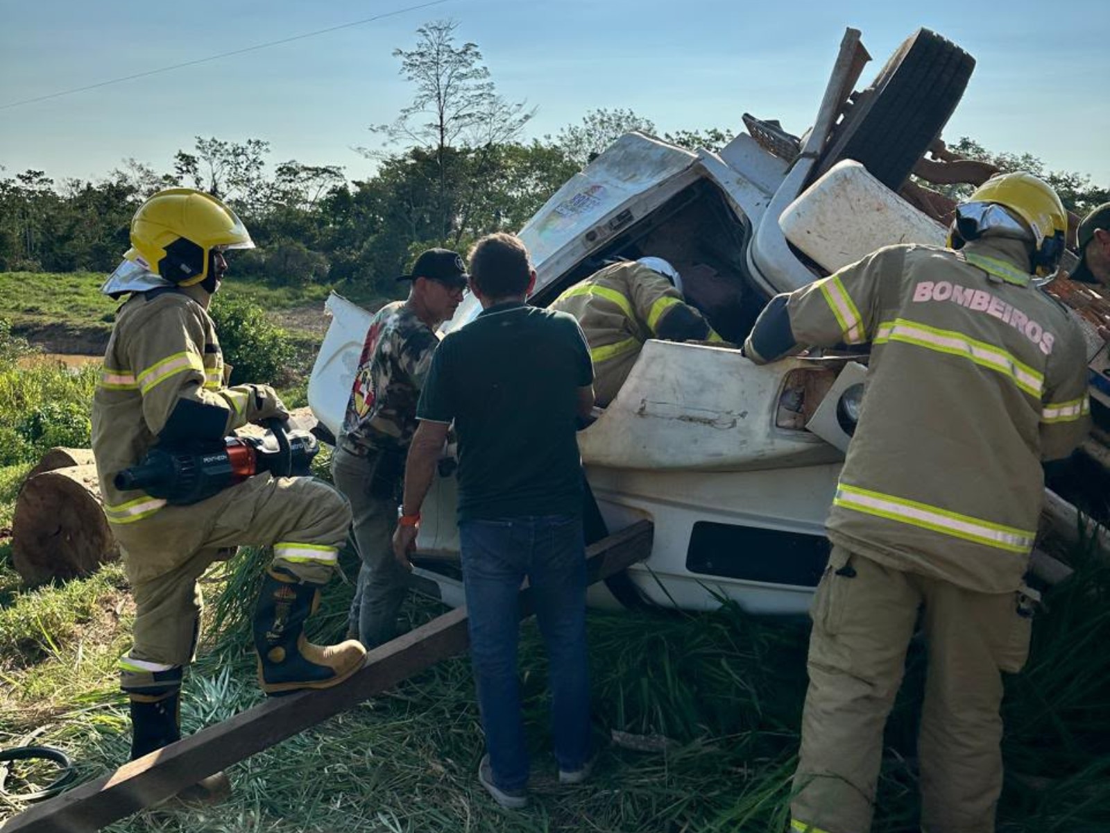 Motorista e passageiro ficam presos às ferragens de carreta que tombou com toras de madeira no Acre; VÍDEO
