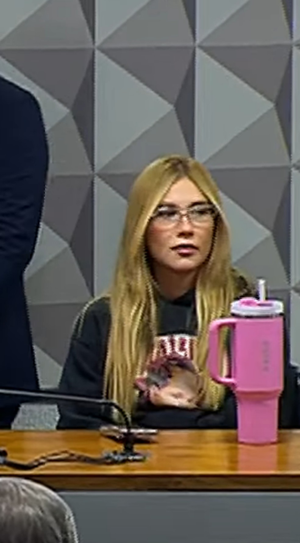 Virg&iacute;nia Fonseca vai &agrave; CPI de moletom com estampa da filha, Maria Flor, e copo Stanley rosa na mesa &mdash; Foto: Reprodu&ccedil;&atilde;o/YouTube
