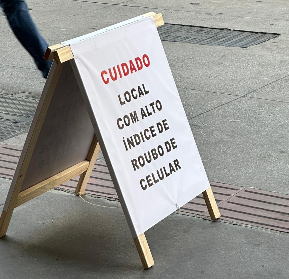 Placa com recado para pedestres e motoristas tomarem cuidado com seus celulares devido ao alto número de roubos na Avenida Brigadeiro Faria Lima, Zona Oeste de São Paulo — Foto: Kleber Tomaz/g1