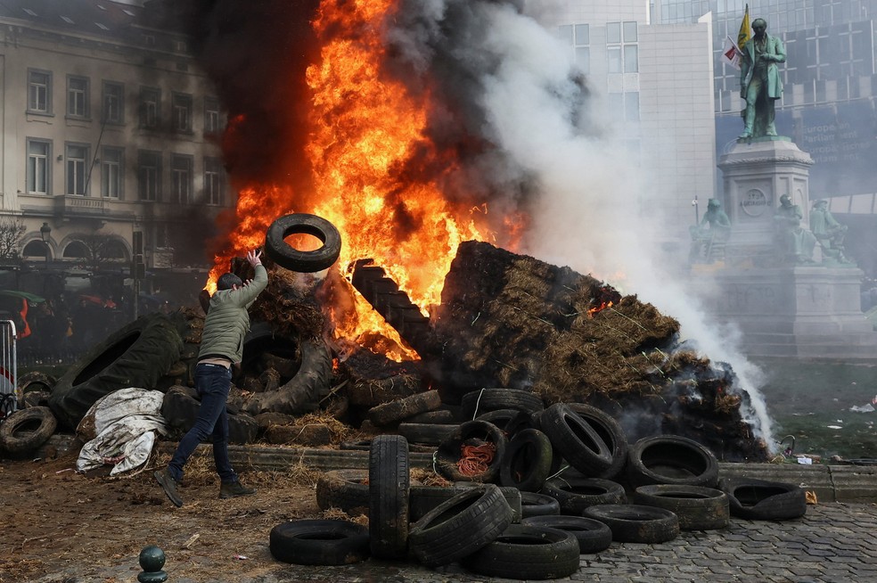 Manifestante atira pneu em fogo durante protesto de agricultores contra o acordo entre União Europeia e Mercosul em Bruxelas, em 18 de dezembro — Foto: REUTERS/Yves Herman
