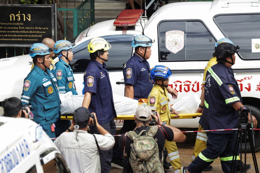 Equipes de emergência carregam corpo coberto para fora da escola Debsirin Nonthaburi, em Bangkok, na Tailândia, após ataque a tiros em 7 de agosto de 2026. — Foto: REUTERS/Athit Perawongmetha