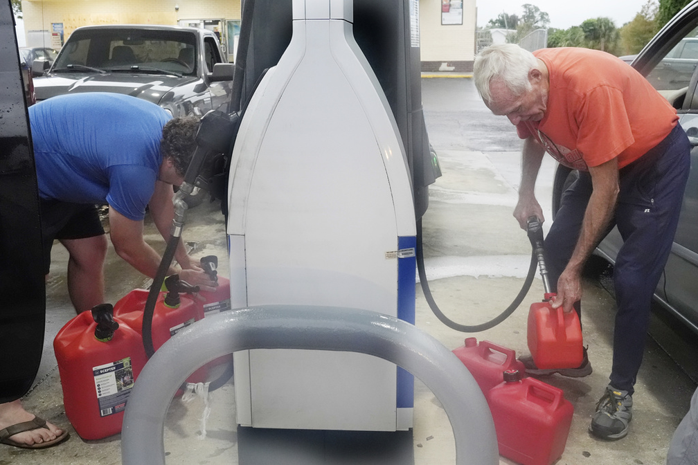 Homens abastecem galões de gasolina de reserva em Port Charlotte, na Flórida, antes da chegada do furacão Milton, em 9 de outubro de 2024. — Foto: Marta Lavandier/ AP