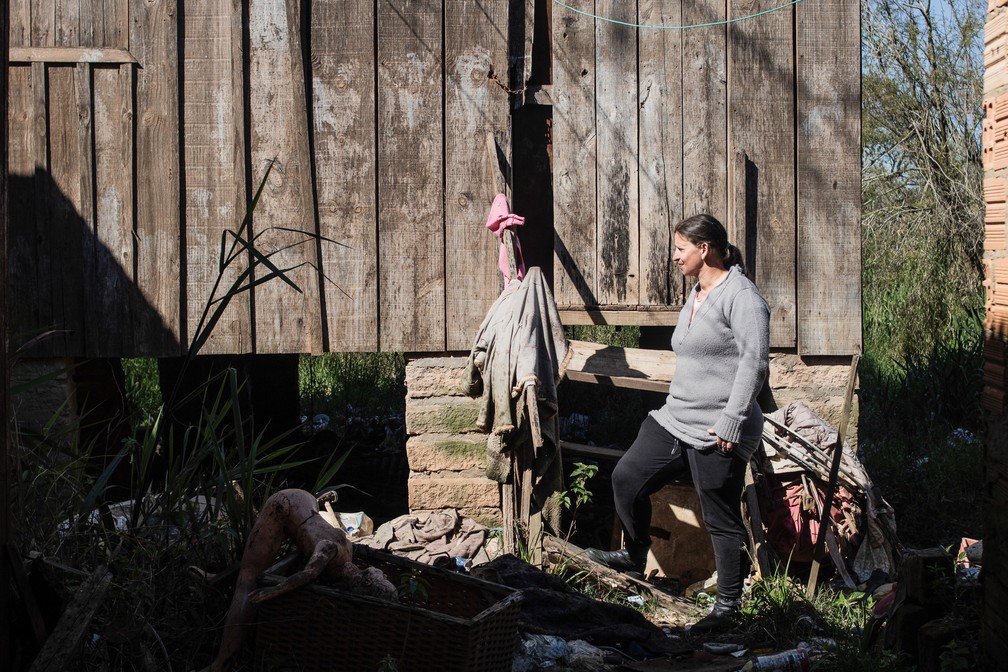Rosimere Rocha da Silva na frente da casa que ela perdeu depois das enchentes de maio de 2024 na Ilha das Flores, em Porto Alegre — Foto: Anna Ortega/g1