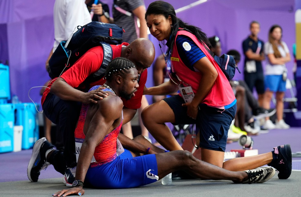 Noah Lyles é tratado pela equipe médica após a final dos 200 metros — Foto: Petr David Josek/AP
