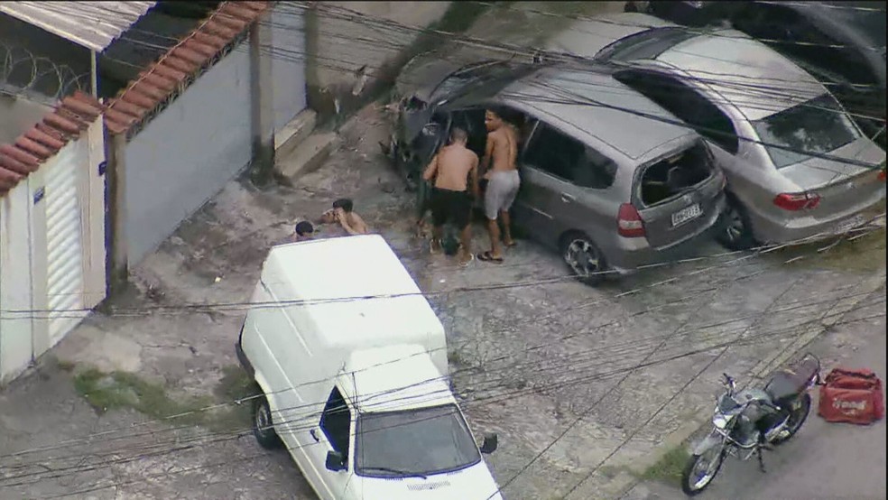 Homens mexem no corpo de PM — Foto: Reprodução/ GloboNews