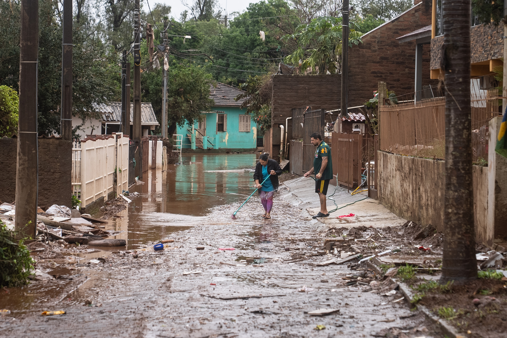Diego Brizola e a mãe, Maria, limpam a lama acumulada em frente à casa da família no bairro de Hidráulica, em Lajeado, que foi muito atingido pela cheia do Rio Taquari — Foto: Fábio Tito/g1
