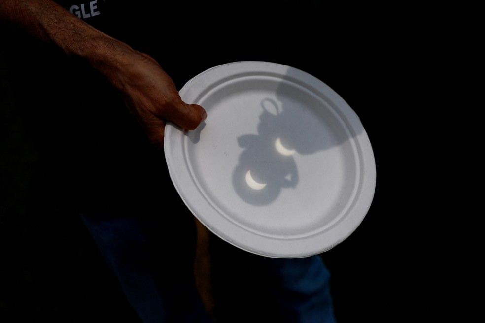 Pessoa segura um prato durante o eclipse solar, quando a Lua encobre o Sol, em Eagle Pass, no Texas. — Foto: Reuters/Christian Monterrosa