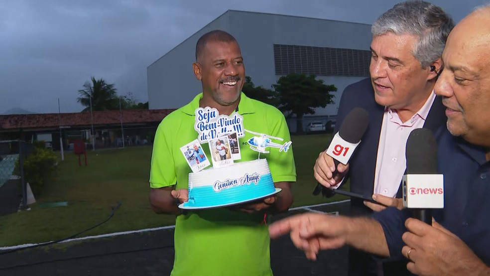 Produtor Enildo Viola com bolo de boas-vindas para Genilson Araújo — Foto: Reprodução/ TV Globo