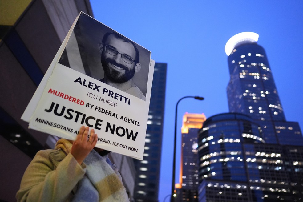 Uma pessoa segura um cartaz com a imagem de Alex Pretti durante um protesto em frente ao escritório da senadora Amy Klobuchar, democrata de Minnesota, na segunda-feira (26), em Minneapolis. — Foto: AP/Adam Gray