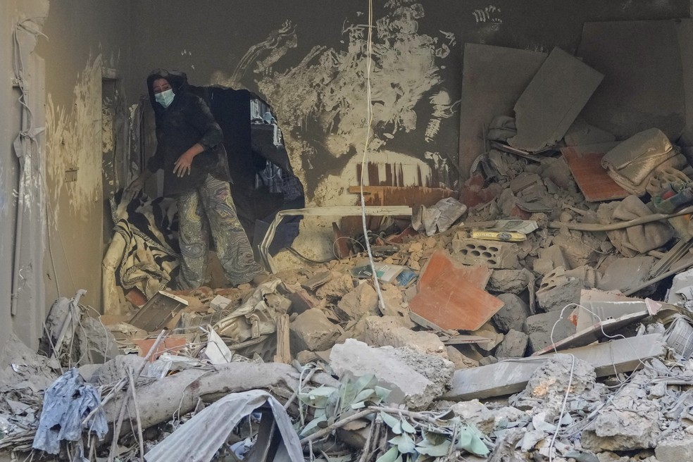 Uma moradora de um prédio danificado em um ataque aéreo israelense retorna para recolher os pertences de sua família no local do ataque aéreo israelense de quinta-feira em Beirute, Líbano — Foto: AP/Hassan Ammar