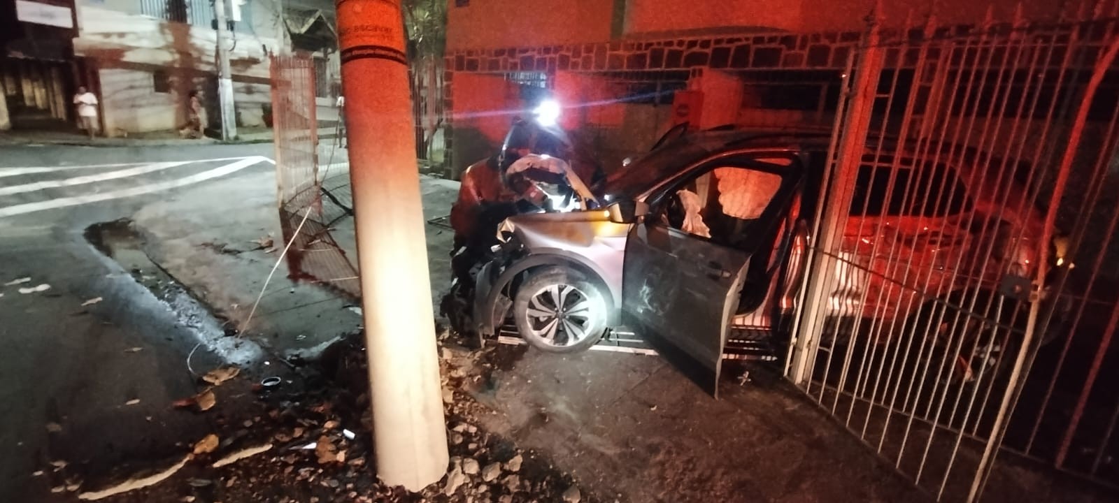 Carro fica destruído após bater em poste e grade de garagem no Centro de Juiz de Fora