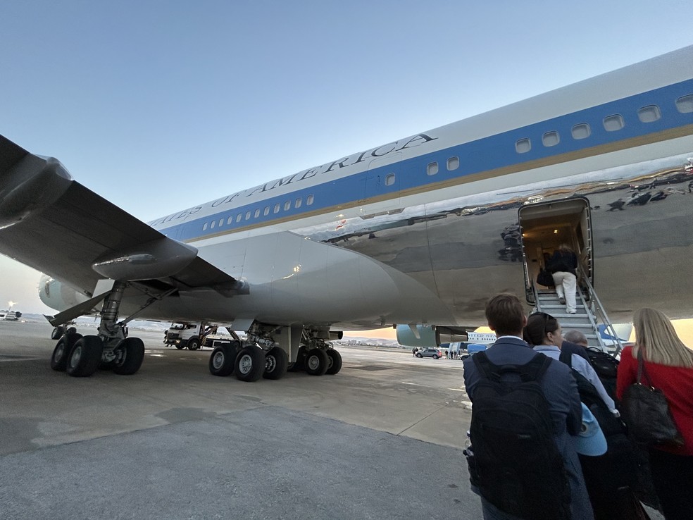 Imprensa embarcando no Air Force One e, ao fundo, caminhão de transporte de alimentos posicionado na parte dianteira do avião e que, segundo relatos, foi utilizado para transportar Donald Trump até a outra aeronave. — Foto: Pool