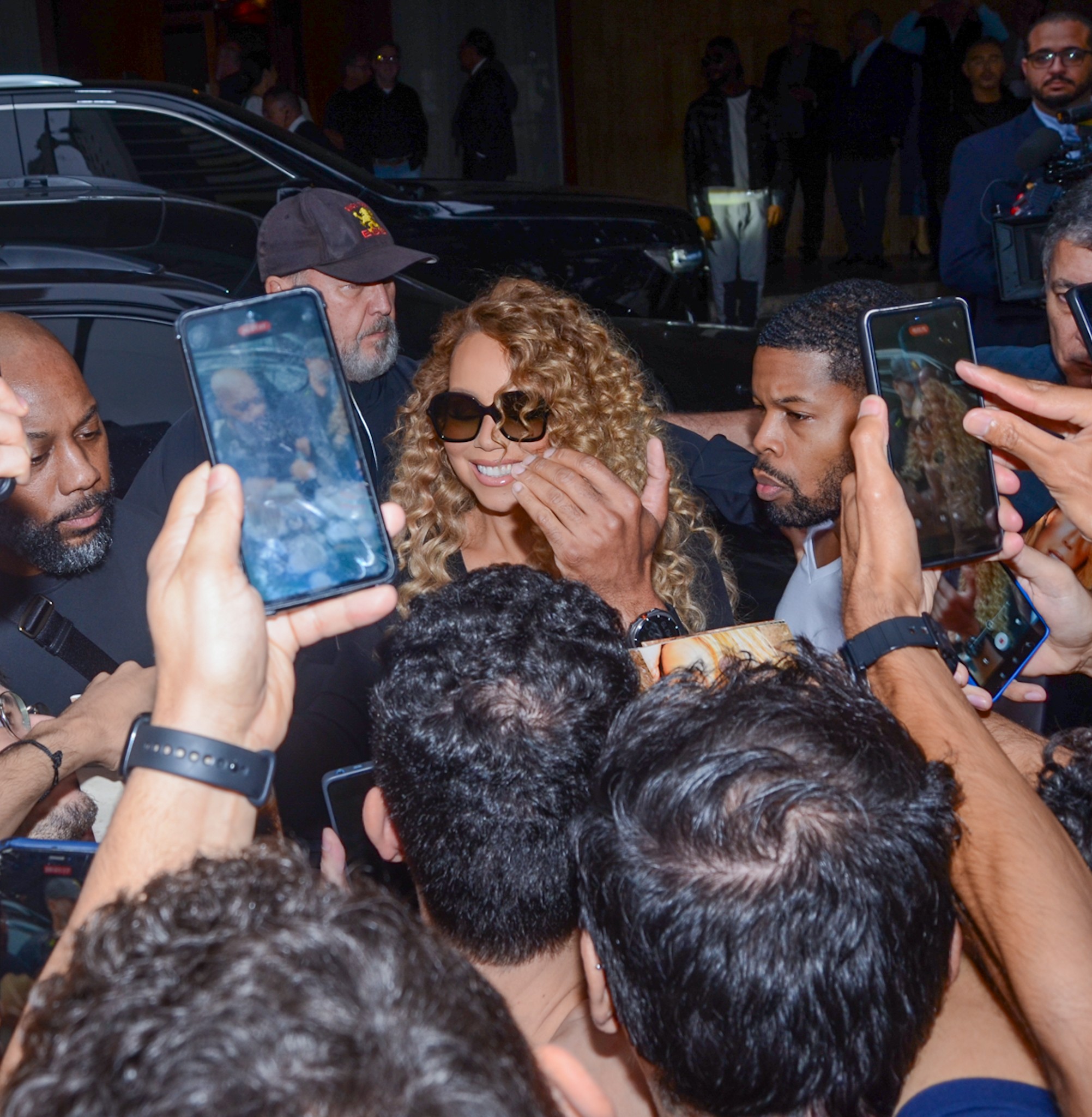 Sorridente, Mariah Carey atende fãs na porta do hotel em São Paulo