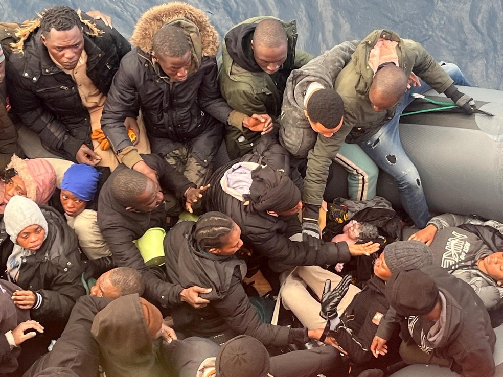 Migrantes cuidam de um bebê recém-nascido logo após o parto enquanto sua mãe descansa dentro de um bote com 60 pessoas que foram resgatadas na sequência da ilha de Lanzarote, nas Ilhas Canárias, Espanha, na segunda-feira (6) — Foto: Salvamento Marítimo da Espanha via Reuters