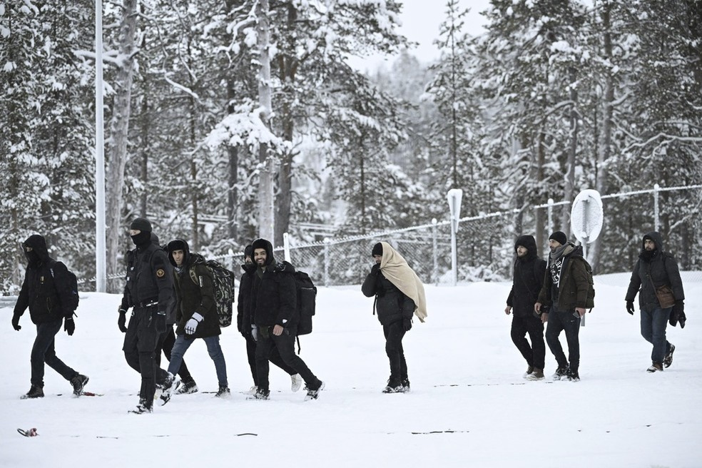 Imigrantes caminham escoltados por guardas finlandeses após chegarem à Finlândia a partir da fronteira com a Rússia, em 25 de novembro de 2023. — Foto: Emmi Korhonen/Lehtikuva via AP
