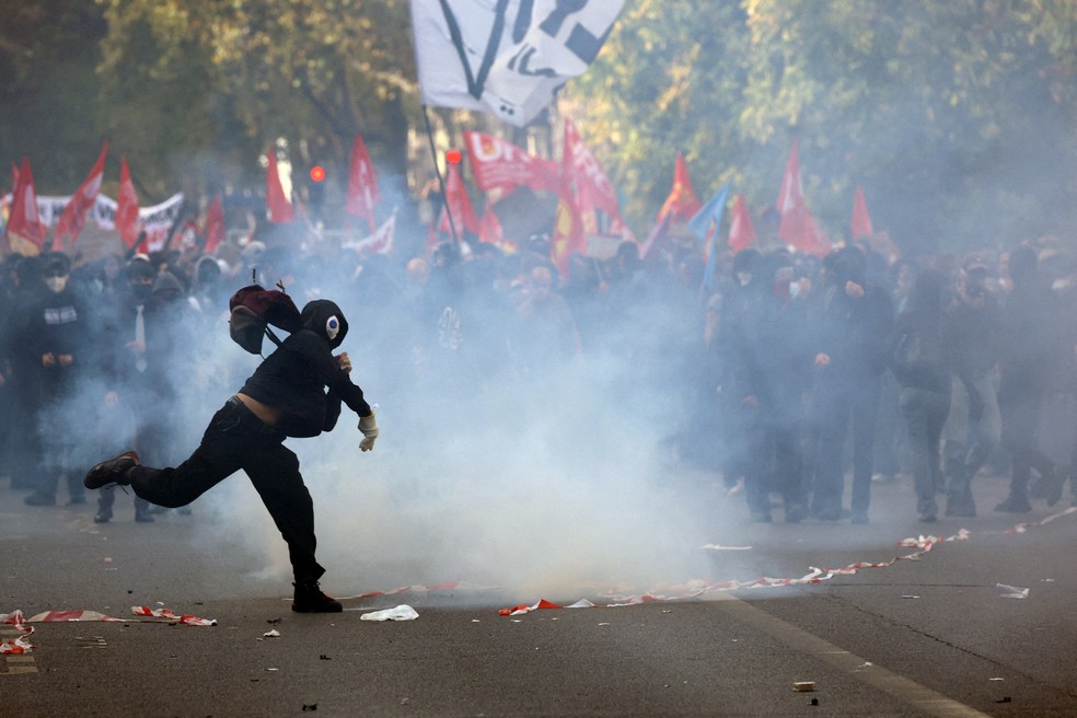 Um manifestante mascarado atira um objeto em meio a confrontos com a polícia francesa durante uma manifestação de estudantes do ensino médio e universitário. — Foto: Yves Herman/Reuters