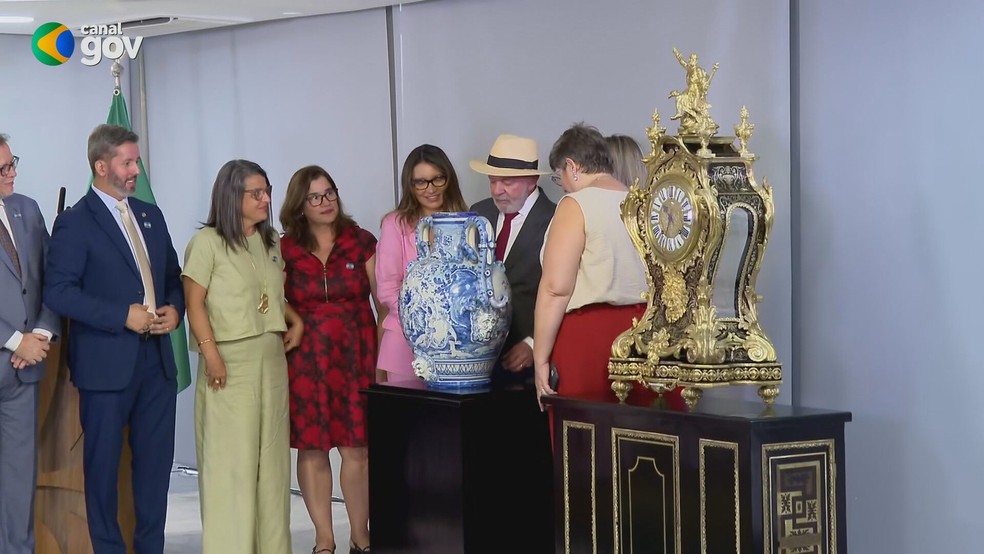 Lula e Janja observam vaso e relógio restaurados — Foto: Reprodução