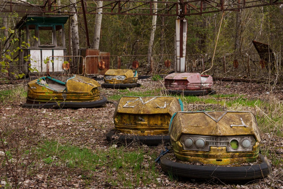 Carrinhos de bate-bate permanecem parados em um parque de diversões tomado pela vegetação em Pripyat, na Ucrânia, cidade abandonada após o desastre nuclear — Foto: AP Photo/Evgeniy Maloletka