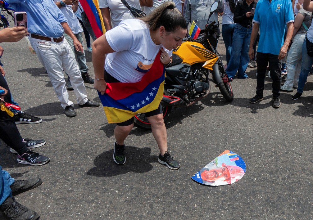 Mulher cospe em foto de Maduro em protesto em Maracaibo, na Venezuela — Foto: REUTERS/Isaac Urrutia