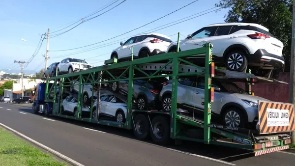 Carro fica destruído após cair de caminhão-cegonha que entalou em