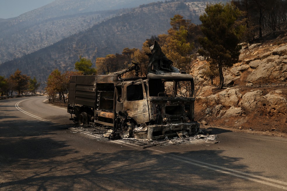 Caminh&atilde;o dos bombeiros destru&iacute;do pelo fogo permanece em uma estrada ap&oacute;s a passagem de um inc&ecirc;ndio florestal em Porto Germeno, na Gr&eacute;cia, nesta segunda-feira (3). &mdash; Foto: Stelios Misinas/Reuters