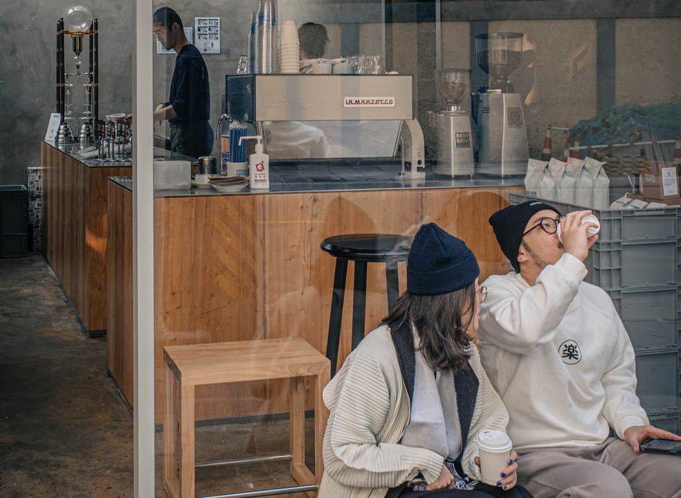 Imagem de dois jovens em uma cafeteria de Pequim. — Foto: Zhouxing Lu/unplash